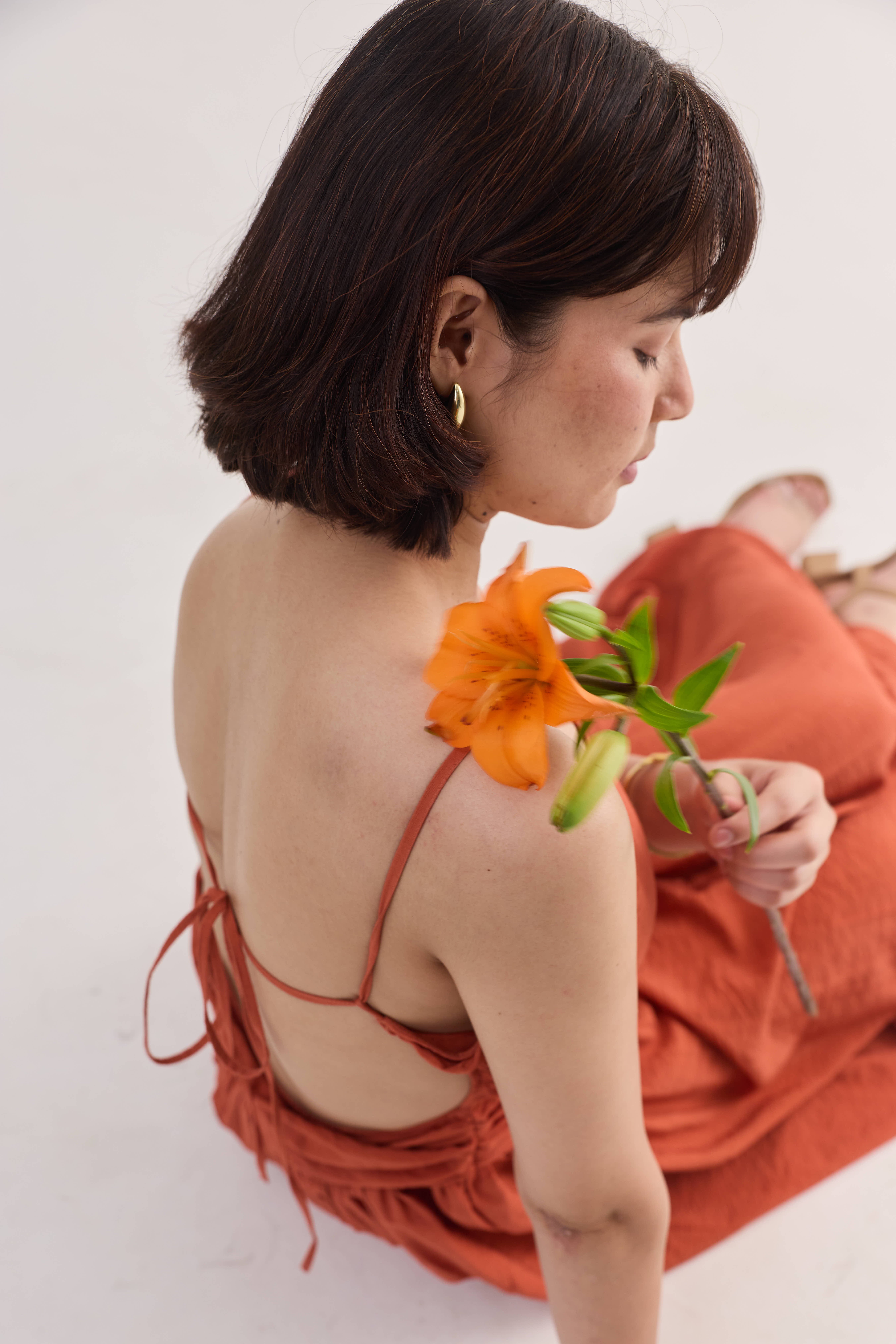 Editorial portrait with flower and warm draped garment