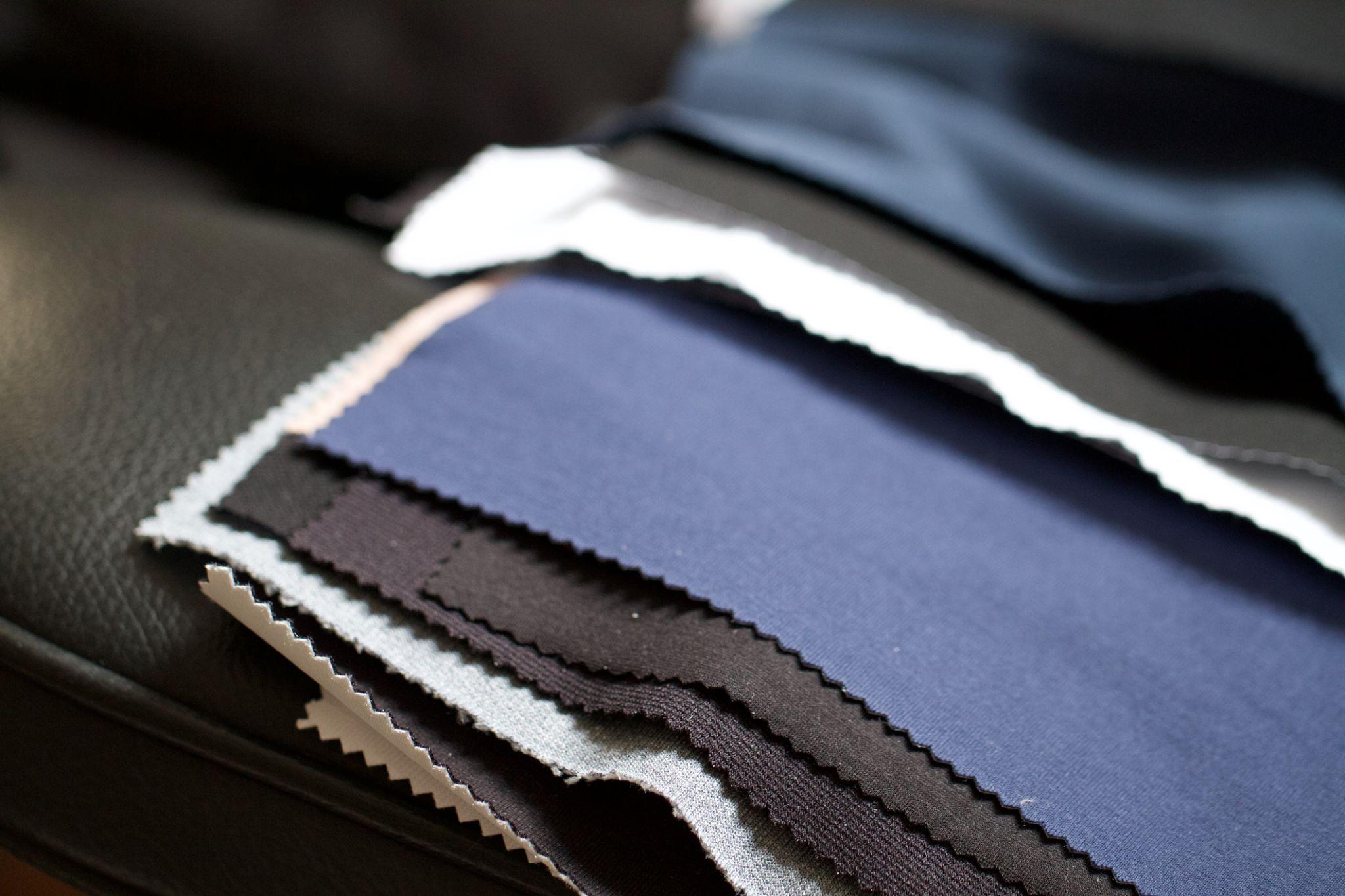 Layered fabric swatches in navy, black, and pale blue