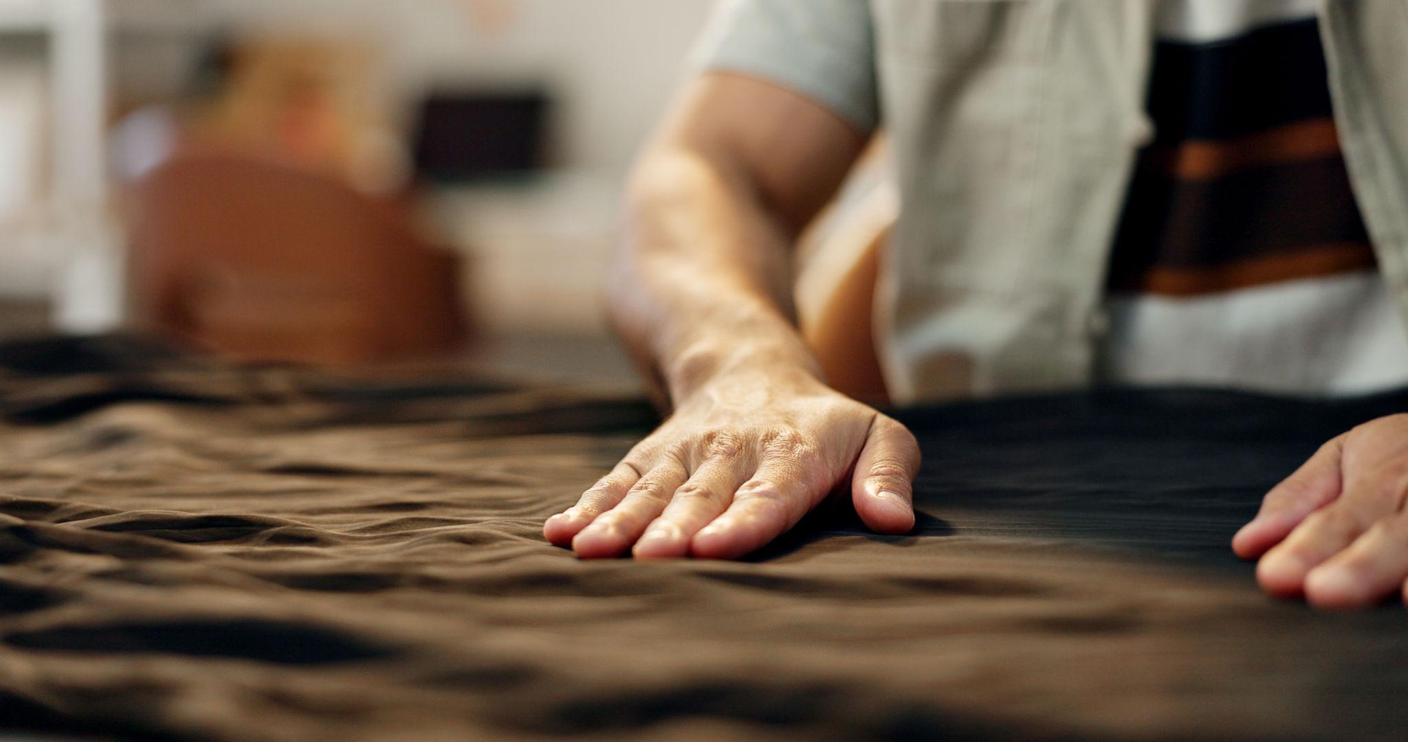 Hand smoothing dark fabric during garment making